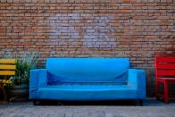 A blue couch between a yellow and a red bench.
